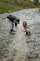 two happy little girls of European appearance playing in puddles during rain in summer. children are playing in the rain. child playing in nature outdoors. the girl enjoys the rain. photo