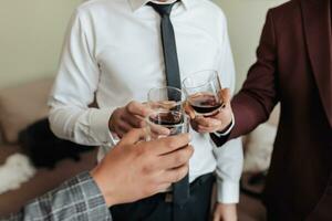 Cropped photo. Men hold glasses of whiskey and clink glasses. Beautiful male hands. Business style. Alcohol photo