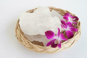 Crystal clear alum stones or Potassium alum on basket, decorated with flowers. Useful for beauty and spa treatment. Use to treat body odor under the armpits as deodorant and make water clear. photo