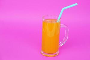 Glass mug of orange juice with drinking straw.  Pink background. Concept, morning refreshing beverage. Sweet, testy and high vitamin C. photo