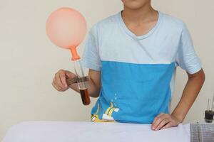 Closeup boy hold test tube with balloon. Science experiment. The expanding of air pressure , reaction of chemical substance. Concept, Science camp activity. Learning by doing. photo