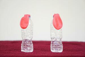 Two pink balloons on top of bottles. Concept, science experiment about reaction of chemical substance, vinegar and baking soda that cause balloon inflat. First step of experiment photo