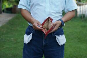 Close up man shows his empty wallet and jeans pockets. Concept, Poor, bad economic crisis. Financial problems. Broke or less money at the end of month. No money. photo