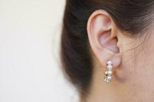Close up fashionable pearl earring, pendant on woman's ear. Concept, beauty and fashion accessory to decorate on body part. Jewelry and Femininity. photo