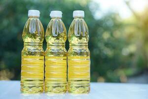 Three bottles of vegetable oil for cooking. Outdoor background. Extracted from seeds or from other parts of plants, such as sunflower seeds, soy beans, olive, palm fruits. photo