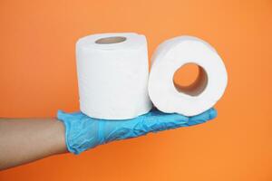 Close up hand hold two rolls of white tissue paper, isolated on orange background.Concept, cleaning tool, hygienic to wipe dirty and absorb wet ,use tissue paper for hygienic and sanitary.Toilet paper photo