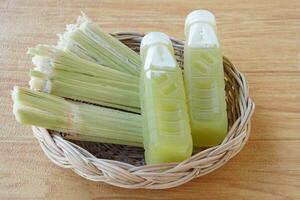 Closeup bottles of fresh sugar cane juice, put on basket. Concept, healthy natural beverage made from agriculture crop. Homemade drinks, has medicinal and herbal properties photo