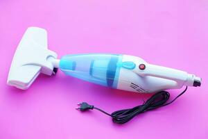 Portable electric vacuum cleaner on pink background. Concept, Household electric appliance device for cleaning. Get rid of dust or scraps. photo