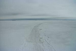 invierno la carretera en el hielo de un amplio congelado río va más allá el horizonte, invierno paisaje foto