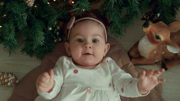 Lycklig 1 år gammal barn lögner nära de jul träd och skrattar. video
