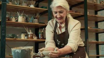 pottenbakkerij kunst, senior vrouw, ouderen leeftijd, creatief vrije tijd. senor vrouw maakt een kom gedurende pottenbakkerij. video