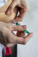 Close up shot of the woman with beautiful hands, preparing hormone medicine and injecting herself to the abdomen with pierced bellybutton. Healthcare photo