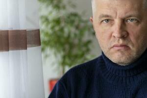 Portrait of the mid aged man with grey hair, wearing warm, dark blue sweater. People photo