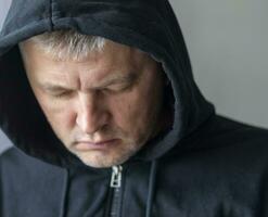 Man looked like hacker in a hood looking at the screen. People photo