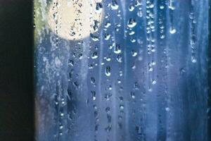 Shot of the window after rain with blurred lights on the background. Concept photo
