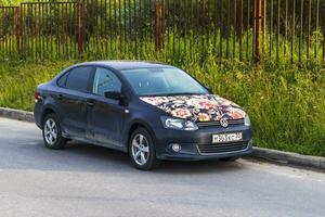 Moscow, Russia - 07.03.2023 - Shot of the car on the side of the road hood of which painted in traditional Russian design called khokhloma. Streets photo