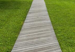 Concept shot of the wooden path laid on the green grass. Background photo
