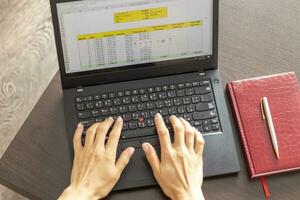 Shot of a woman working on the laptop showing an excel sheet on the screen with bank loan amortization table. Finance photo