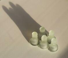 Shot of the chess pieces, pawns, casting shadow in the shape of a crown. Concept photo