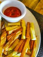 Portion of fries with ketchup sauce on a white plate. photo