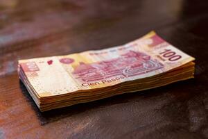 Playa del Carmen Quintana Roo Mexico 2021 Stack of banknotes 100 Mexican pesos on a wooden table. photo