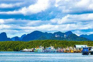 Tropical paradise turquoise water beach limestone rocks fisherboats Krabi Thailand. photo