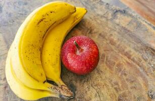 Bananas and red apple fruit on wooden table in Mexico. photo