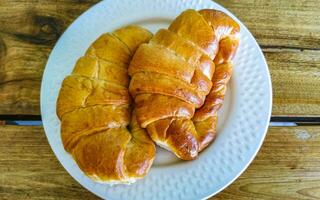 2 croissants on a white plate on a wooden table in Mexico. photo