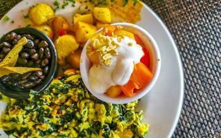 Breakfast scrambled eggs spinach fruit potatoes nicely arranged on plate. photo