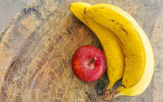 Bananas and red apple fruit on wooden table in Mexico. photo