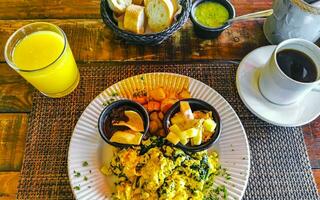 Breakfast scrambled eggs spinach fruit potatoes nicely arranged on plate. photo