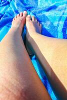 Womens legs and feet on blue beach blanket in Germany. photo