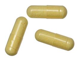 Transparent capsule with yellow powder on isolated background, medical drug photo