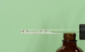 Glass bottles for cosmetics, oils with a pipette on a green background photo
