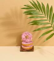 Donut covered with pink glaze and sprinkled with multi-colored sprinkles, brown background photo