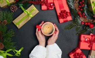 hembra manos participación un rojo taza de café entre regalos en un negro mesa foto