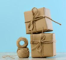 The box is packed in brown craft paper and tied with a rope on a blue background, gift photo