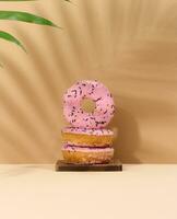 Donut covered with pink glaze and sprinkled with multi-colored sprinkles photo