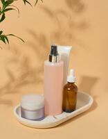 conjunto de facial cuidado productos cosméticos en un beige antecedentes. tónico, crema, loción y petróleo foto