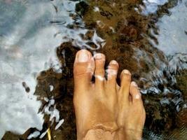 un de la persona pies en el agua con agua salpicaduras en ellos foto