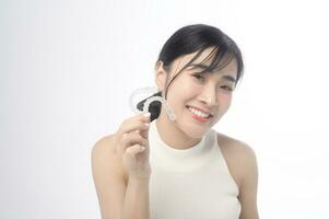 Young smiling woman holding invisalign braces over white background studio, dental healthcare and Orthodontic concept. photo