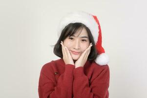 Young happy woman in santa claus hat wearing red sweater over white background, Christmas concept photo