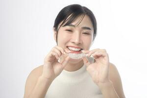 Young smiling woman holding invisalign braces over white background studio, dental healthcare and Orthodontic concept. photo