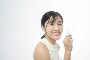 Young smiling woman holding invisalign braces over white background studio, dental healthcare and Orthodontic concept. photo