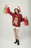 Young happy woman in santa claus hat wearing red sweater over white background, Christmas concept photo