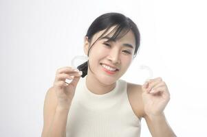 Young smiling woman holding invisalign braces over white background studio, dental healthcare and Orthodontic concept. photo