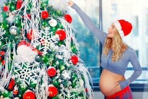 embarazada mujer adorna Navidad árbol foto
