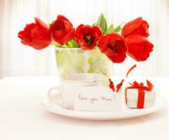 Red tulips and cup of tea photo