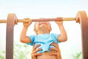 pequeño chico captura arriba en el horizontal bar foto