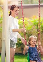 Mom rocks her daughter on a swing photo